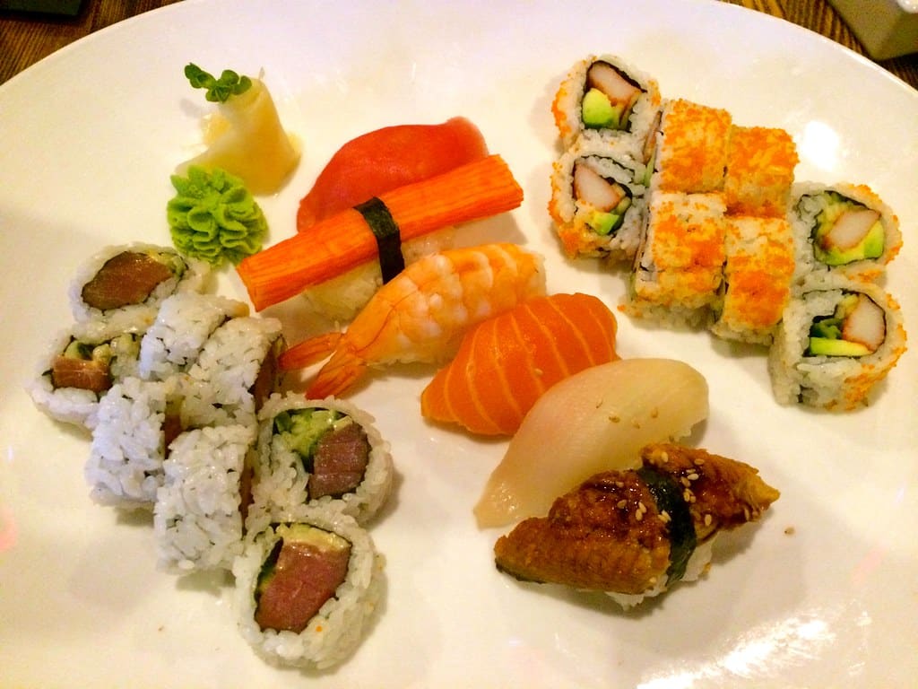 A plate of assorted sushi rolls and nigiri with wasabi and pickled ginger