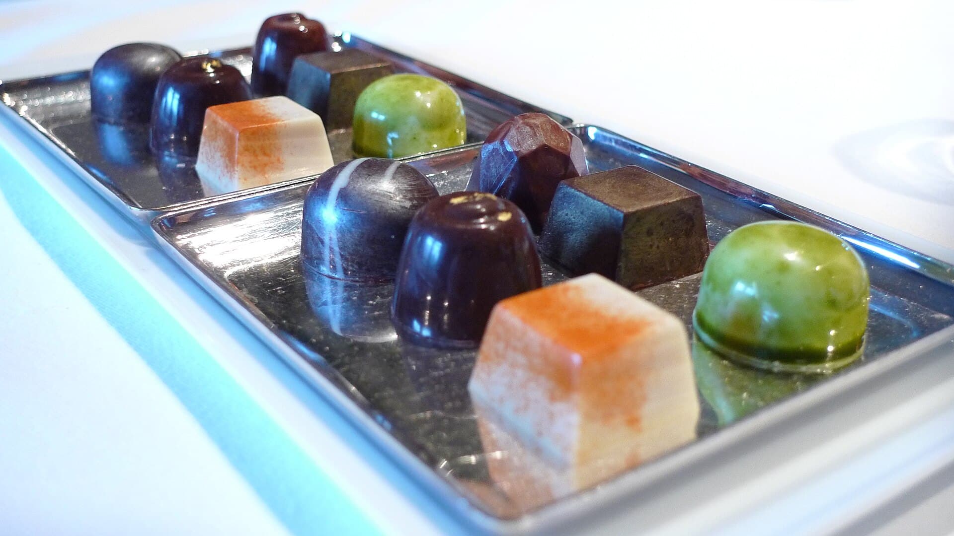 Rows of glossy handmade chocolate truffles and bonbons arranged on silver trays