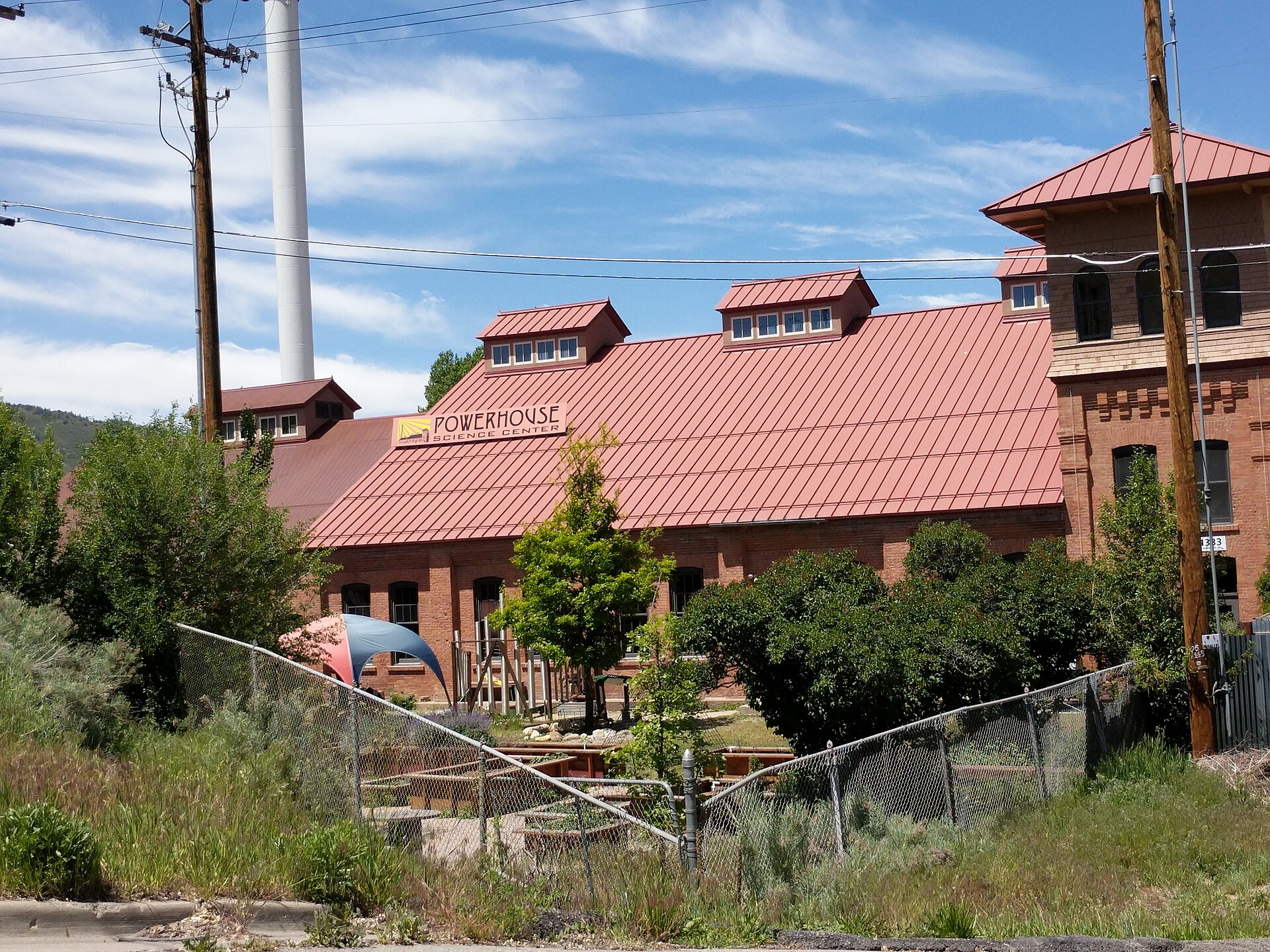 The historic red-brick Powerhouse building in Durango, with its red metal roof, dormer windows and tall white smokestack under a blue sky