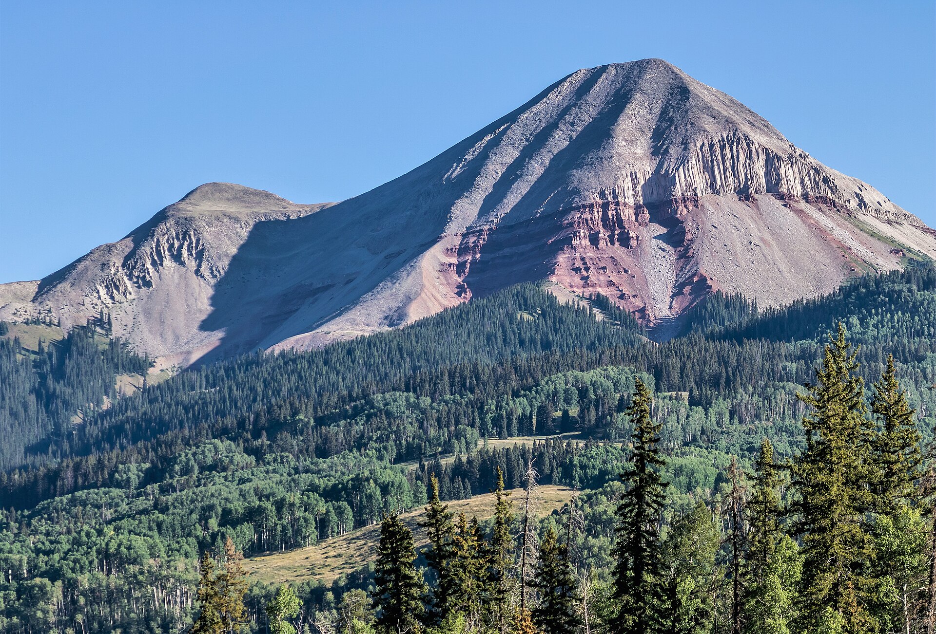Engineer Mountain's rocky red and grey summit rising above green forest along US-550 north of Durango, Colorado