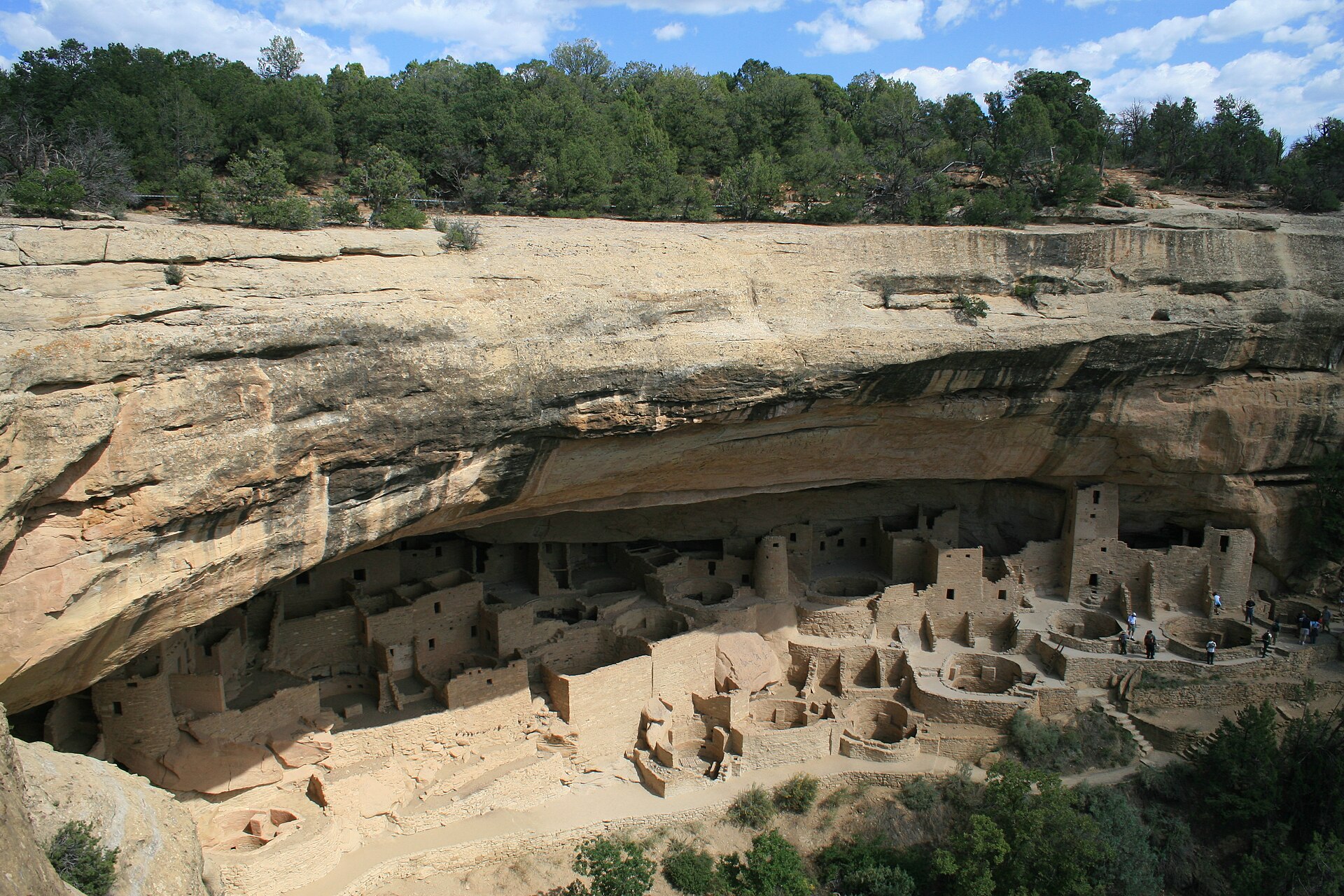 Cliff Palace at Mesa Verde National Park, ancient stone dwellings and towers tucked beneath a sandstone alcove under a blue sky