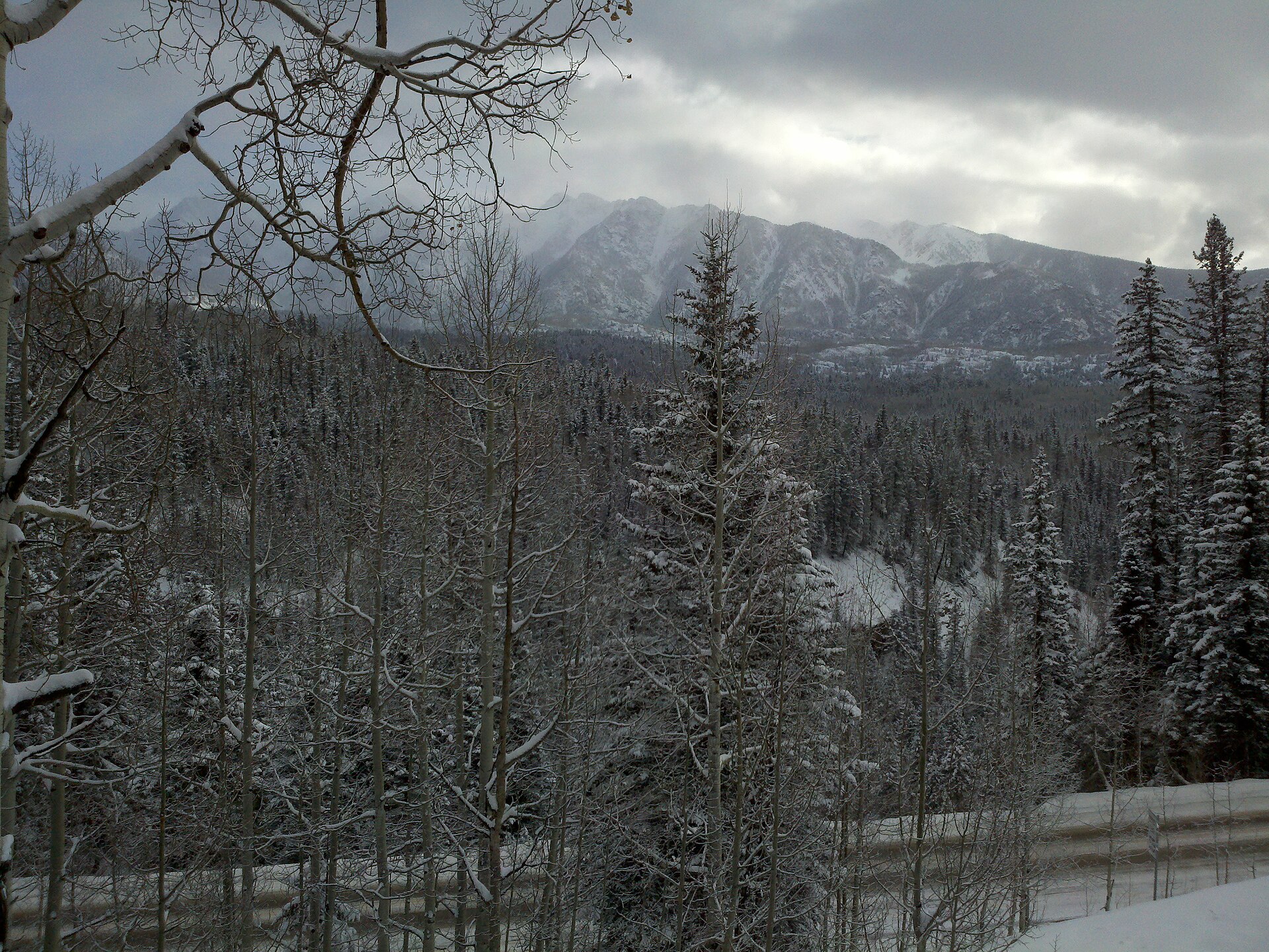 Snow-dusted aspen and spruce forest at Purgatory Resort with the snowy San Juan peaks under a winter sky