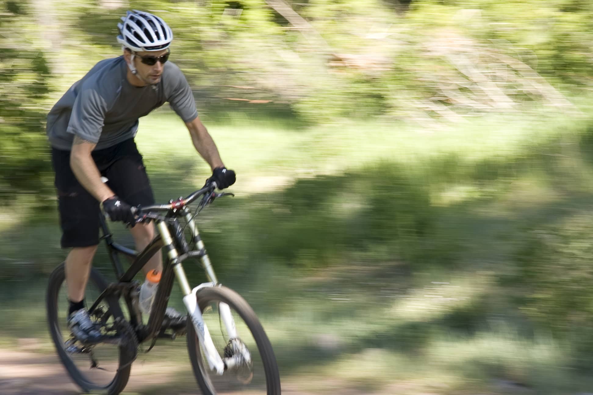 Mountain biker riding green, tree-lined singletrack near Durango, Colorado
