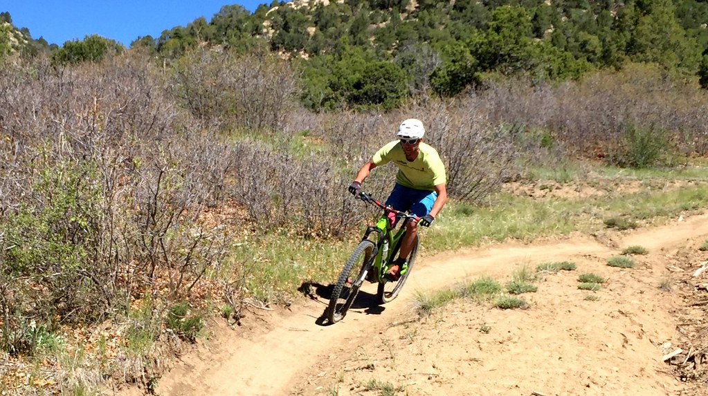 Mountain biker riding a curving dirt singletrack through scrub oak and juniper in Durango's Horse Gulch trail system